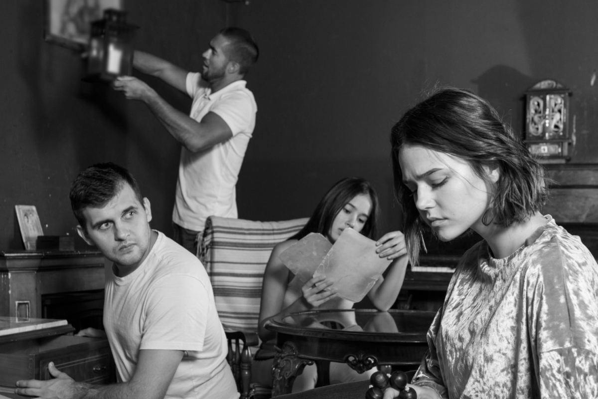 Young people looking at old wooden rosary while pursuing investigation in escape room with antique furniture