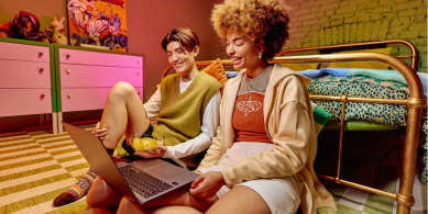 Friends sitting on floor of bedroom looking at laptop