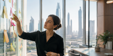 Marketing leader developing ideas on a glass wall in a modern Dubai office, reflecting ambition, experimentation and visible impact.